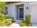 Inviting entrance with a stylish navy blue door, decorative wreath, and well-maintained landscaping at 30273 Marquette Ave, Wesley Chapel, FL 33545