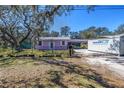 Charming light purple single-story home with mature tree and black chain link fence at 5010 109Th N Way, St Petersburg, FL 33708