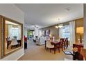 Open-concept living and dining area with neutral carpet, white curtains, and natural light streaming through the windows at 5646 Sunset Falls Dr, Apollo Beach, FL 33572