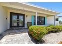 Elegant front entrance showcasing a double door, well-maintained garden, and beautiful window shutters at 6322 Cocoa Ln, Apollo Beach, FL 33572