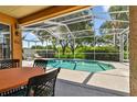 Screened-in lanai with a table and chairs overlooking a sparkling swimming pool and lush backyard at 13028 Prestwick Dr, Riverview, FL 33579