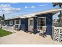 Inviting single-story blue home with a bright white awning, chairs, and potted plants on the front patio at 13920 Berkowitz Ave, Hudson, FL 34667