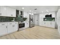 Well-lit kitchen featuring white cabinets, stainless steel appliances, and a green tile backsplash at 14170 Fennsbury Dr, Tampa, FL 33624