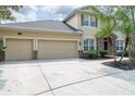 Beige two-story home boasting a three-car garage and well-maintained landscaping at 16170 Colchester Palms Dr, Tampa, FL 33647