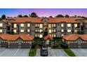Lovely condo exterior with garages, a tiled roof, neat landscaping, and plenty of parking spots at 18107 Peregrines Perch Pl # 6303, Lutz, FL 33558