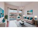 Bright living room with elegant chandelier and sliding glass doors to balcony at 18107 Peregrines Perch Pl # 6303, Lutz, FL 33558