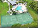 An aerial view showcasing a community pool, spa, clubhouse, and tennis courts surrounded by lush landscaping at 2355 Bentley Dr, Palm Harbor, FL 34684