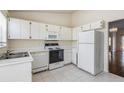 A kitchen features white cabinets, appliances, and tile flooring with a view into an adjacent room at 2355 Bentley Dr, Palm Harbor, FL 34684