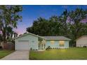 Charming single-story home with green exterior, manicured lawn, and attached one car garage at 2415 Devonwoode Pl, Seffner, FL 33584