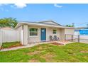 Inviting single-story home with a blue door, outdoor seating, and manicured lawn at 3927 Spence Ave, Tampa, FL 33614