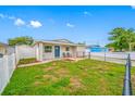 Quaint single-story house featuring a grassy front yard, blue door, and charming, fenced outdoor seating at 3927 Spence Ave, Tampa, FL 33614