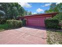 Garage with a two-car garage door and mature landscaping at 4388 Tiffin Ave, Spring Hill, FL 34609