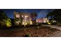 Nighttime view of a stucco two-story house with illuminated landscaping, creating a welcoming ambiance at 6251 4Th S Ave, St Petersburg, FL 33707