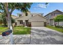 A well-maintained two-story home with a large tree, stone veneer, and a spacious driveway at 7013 Early Gold Ln, Riverview, FL 33578