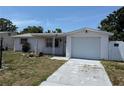 Single-story home with a one car garage, a quaint porch and a green yard at 7021 Mayfield Dr, Port Richey, FL 34668
