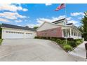 View of home's side showing large garage, brick accents, and American flag at 9830 Caribou Trl, Dade City, FL 33525