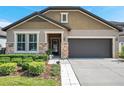 Inviting home with stone accents, a two-car garage, and landscaped front yard at 11314 American Holly Dr, Riverview, FL 33578