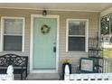 View of home's welcoming front porch with green door and seasonal wreath at 11814 Washington St, Seffner, FL 33584