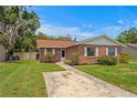 Charming brick home featuring a well-manicured lawn, concrete driveway, and mature trees at 13046 Leverington St, Tampa, FL 33624