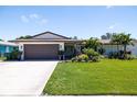 Inviting home featuring a lush green lawn, mature palm trees, and vibrant flower beds under a clear blue sky at 13168 84Th Ter, Seminole, FL 33776