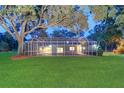 Expansive backyard featuring a screened-in pool enclosure, mature trees, and lush green lawn at 1670 Fox Rd, Clearwater, FL 33764