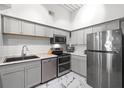 Renovated kitchen featuring stainless steel appliances, gray cabinets, granite counters, and marble flooring at 2410 W Azeele St # 214, Tampa, FL 33609