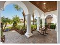Inviting front porch with rocking chairs, brick pavers and beautiful landscaping at 28512 Picana Ln, Wesley Chapel, FL 33543