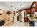 Open kitchen featuring stainless steel appliances, granite countertops, and dark wood cabinetry, seamlessly flowing into living area at 3414 Whittier St, Tampa, FL 33619