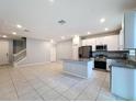 Bright kitchen with a granite island, stainless steel appliances, white cabinets and a clear view of the staircase and entry at 34187 Rogallo Ln, Wesley Chapel, FL 33545