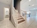 Bright, inviting staircase featuring a white railing, wooden steps, and tiled flooring, leading to an open-concept living area at 34187 Rogallo Ln, Wesley Chapel, FL 33545