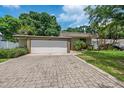 Wide brick driveway leads to a two-car garage of this lovely home with mature trees and a manicured lawn at 4304 N River View Ave, Tampa, FL 33607
