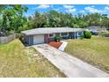 Charming single-story home with lush lawn, mature trees, and a driveway leading to an attached garage at 5068 Lakewood Dr, Ridge Manor, FL 33523