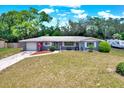 Charming single-story home with lush lawn, mature trees, and a driveway leading to an attached garage at 5068 Lakewood Dr, Ridge Manor, FL 33523