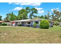 Charming single-story home with lush lawn, mature trees, and a driveway leading to an attached garage at 5068 Lakewood Dr, Ridge Manor, FL 33523
