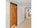Hallway features neutral carpet, bright lighting, and wooden door to apartment #402 at 7432 Sunshine Skyway S Ln # 402, St Petersburg, FL 33711