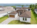 Stylish home with a well-manicured lawn, a paver driveway, and lake views at 8834 Sanders Tree Loop, Wesley Chapel, FL 33545