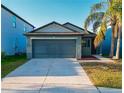 Charming home featuring a two-car garage, beautiful palm tree, and manicured lawn, enhancing its curb appeal at 12720 Hampton Hill Dr, Riverview, FL 33578