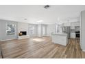 Open-concept living area with fireplace, skylight, wood floors, and access to kitchen at 1555 Newhope Rd, Spring Hill, FL 34606