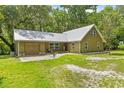 Inviting exterior of a home featuring a well-manicured lawn, metal roof and cozy seating area at 1562 Oakhurst Dr, Brooksville, FL 34601