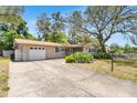 Beautiful home with a manicured lawn, mature trees, and a paved driveway leading to the garage at 1739 Woodridge Dr, Clearwater, FL 33756