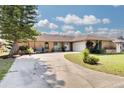 Charming single-story home features a well-manicured lawn, circular driveway, and an attached garage at 1913 Libby Ct, Holiday, FL 34690