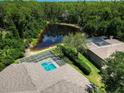 Aerial view of the property featuring a screened pool, pond and lush greenery at 3910 Saywood Ct, Palm Harbor, FL 34685