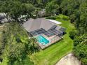 Aerial view of the property featuring a screened pool, well-manicured lawn, and mature trees at 3910 Saywood Ct, Palm Harbor, FL 34685