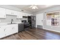 Kitchen with black appliances, white cabinetry, gray walls and laminate flooring at 4517 La Capri Ct, Tampa, FL 33611