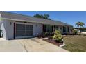 A cozy home featuring colorful landscaping, an attached garage, and a concrete driveway on a sunny day at 6405 Klaus Ct, Port Charlotte, FL 33981