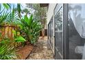 Lush backyard area with tropical plants, wood fencing, and a stone path along the side of the house at 775 N Village N Dr # 106, St Petersburg, FL 33716