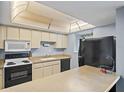 Bright kitchen featuring white cabinets, black appliances, and an island counter, perfect for meal preparation at 775 N Village N Dr # 106, St Petersburg, FL 33716