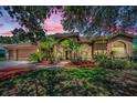 Stunning single-story home at dusk with lush landscaping, arched windows, and a terracotta roof at 1516 E Lake Woodlands Pkwy, Oldsmar, FL 34677