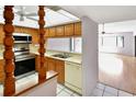 Kitchen with wooden cabinets, stainless steel appliances, and tiled floors that connects to a living room space at 2593 Countryside Blvd # 7305, Clearwater, FL 33761