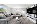 Bright living room featuring gray sectional sofa, stylish lamp, and modern entertainment center at 4521 W North St, Tampa, FL 33614